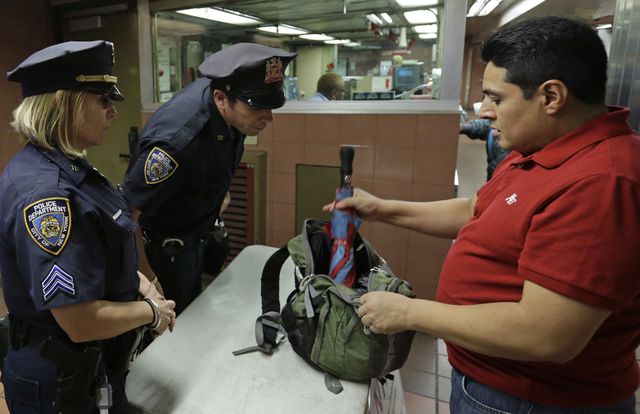 A commuter opens his brief case for police officers to examine its contents